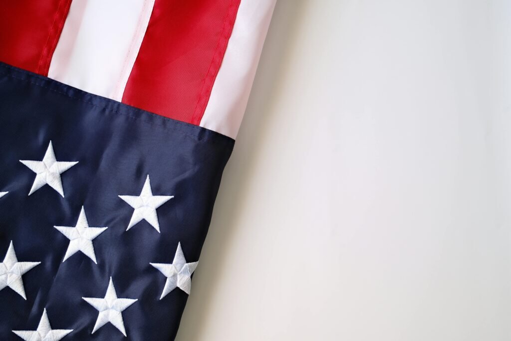 Detailed close-up of United States flag with stars and stripes on a neutral background.